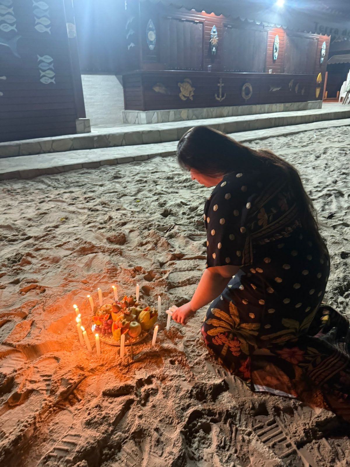 Mãe Lira em ritual com velas e oferendas na areia